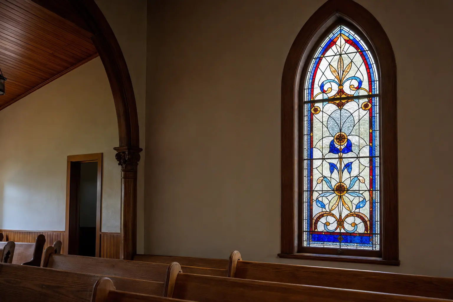 Restored stained glass lancet window in a modest historic church sanctuary