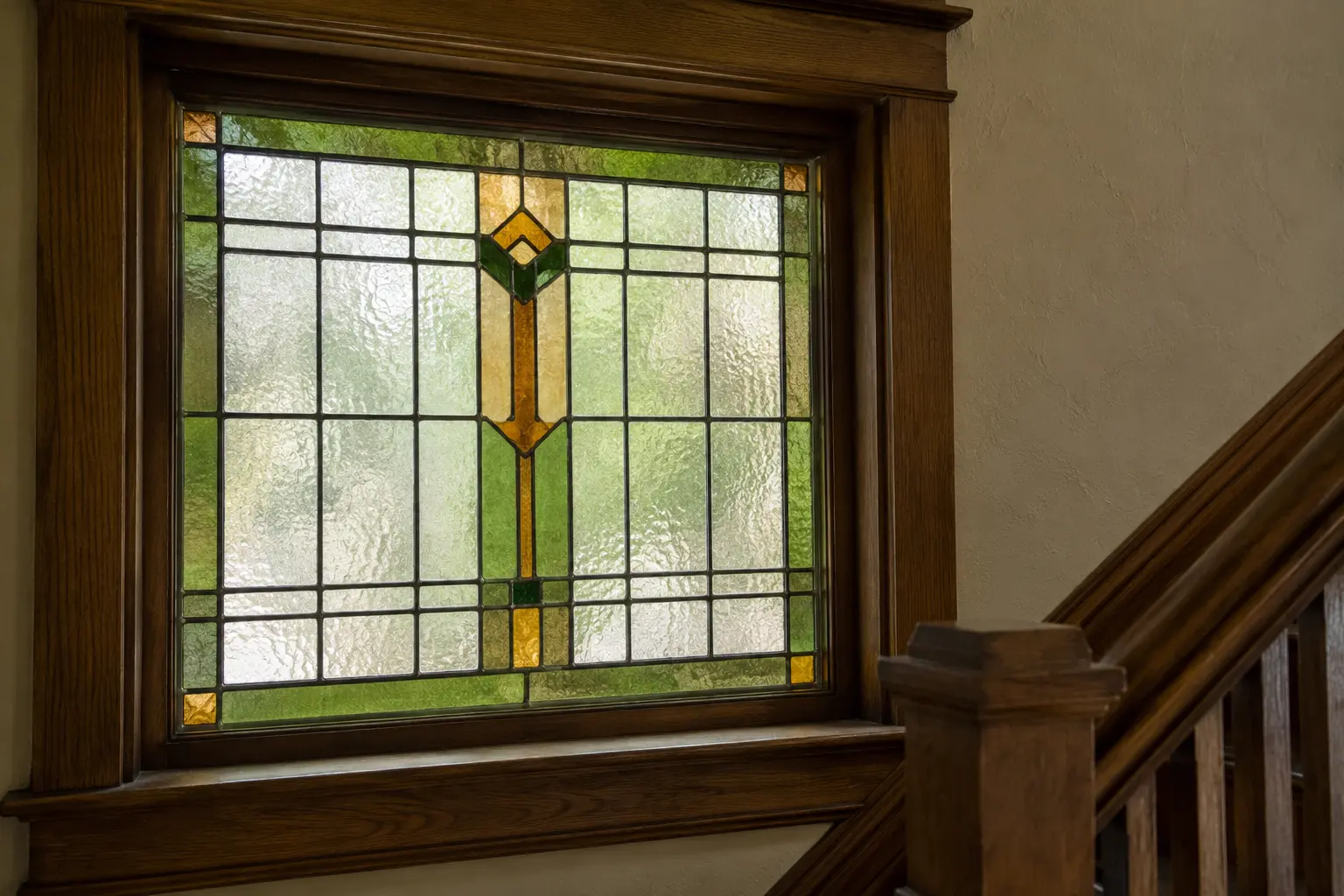Restored Arts and Crafts stained glass window beside an oak staircase